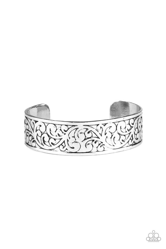 Brushed in an antiqued shimmer, vine-like filigree is embossed across the front of the a thick silver cuff for a whimsical look.
