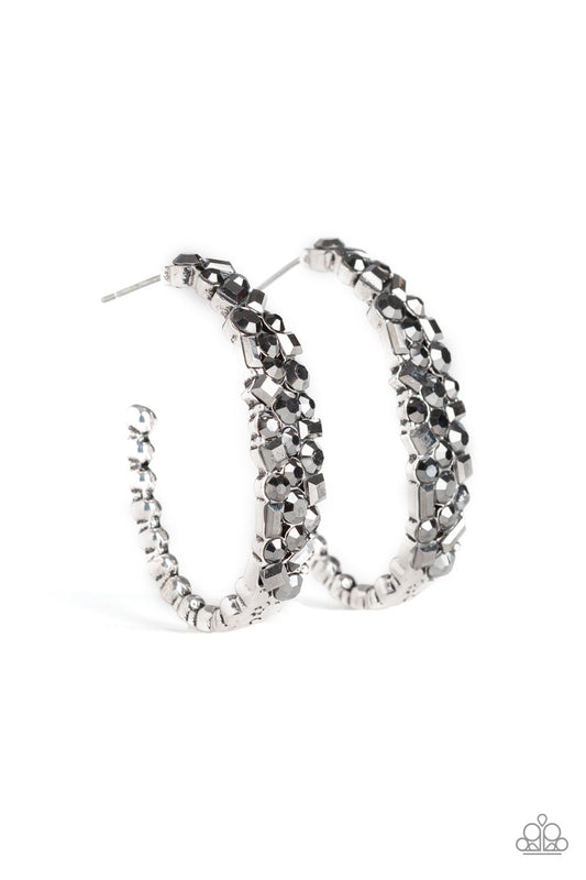 The front of a hook-shaped silver hoop is encrusted in a collision of smoky hematite rhinestones for a blinding look. Earring attaches to a standard post fitting. Hoop measures approximately 1" in diameter.