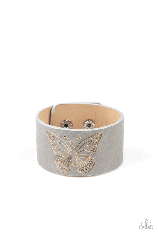 Stamped in a whimsical butterfly, a rustic piece of gray leather wraps around the wrist for a seasonal flair. Features an adjustable snap closure.