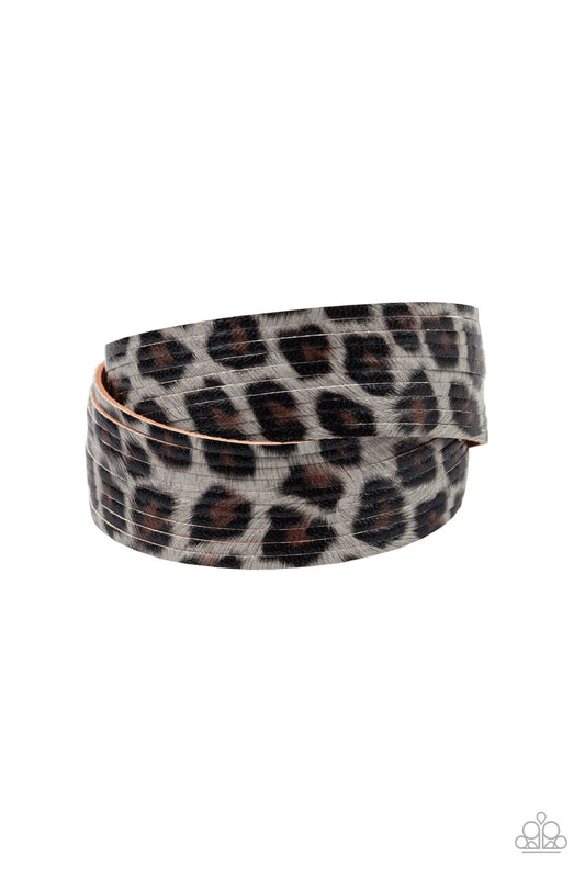 Painted in a lifelike gray, brown, and black cheetah print, thick leather bands have been spliced into layers that wave across the wrist for a wild look. Features an adjustable snap closure.