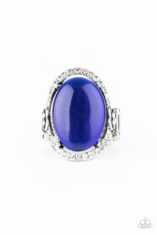 An oval blue cat's eye stone is nestled inside a ring of white rhinestones featuring dainty heart details, creating a charming centerpiece atop the finger. Features a stretchy band for a flexible fit.