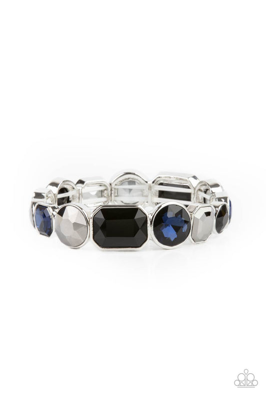 Encased in sleek silver frames, a smoldering collection of round and emerald cut black, blue, and hematite rhinestones glide along stretchy bands around the wrist, creating a sparkly industrial statement piece.
