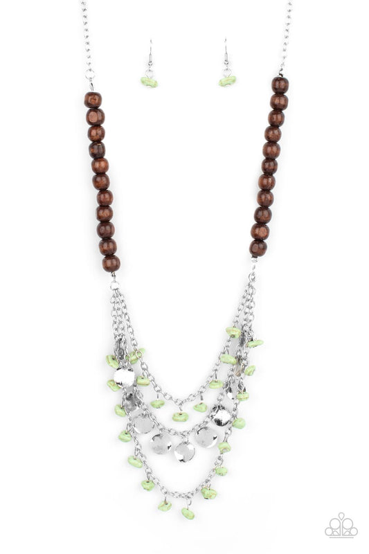 Adorned with green pebbles and hammered silver discs, three silver chains layer from strands of brown wooden beads, creating an earthy fringe below the collar. Features an adjustable clasp closure.