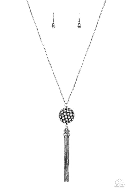 Infused with gunmetal studded fittings, a glittery collection of sparkly white rhinestones coalesce into a dramatic pendant at the bottom of a lengthened gunmetal chain. Capped in a rhinestone dotted frame, a shimmery gunmetal tassel streams out from the blinding pendant for a flirtatious finish. Features an adjustable clasp closure.