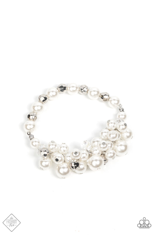White--Paparazzi Jewelry  A strand of pearly white beads, interspersed with faceted silver accents, gives way to an effervescent cluster of luscious pearls. Accented with iridescent and metallic beads, the bubbly cluster is threaded along stretchy bands for a glamorous look around the wrist.