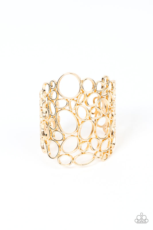 Varying in shape and size, asymmetrical gold circular frames delicately connect into an effervescently abstract cuff around the wrist.