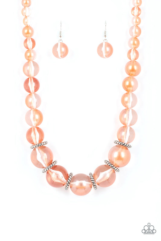 Lightly brushed in a pearly coral shimmer, glassy translucent beads gradually increase in size as they are threaded along an invisible wire below the collar. Textured silver rings separate the largest beads, adding grounding accents to the opalescent display. Features an adjustable clasp closure.