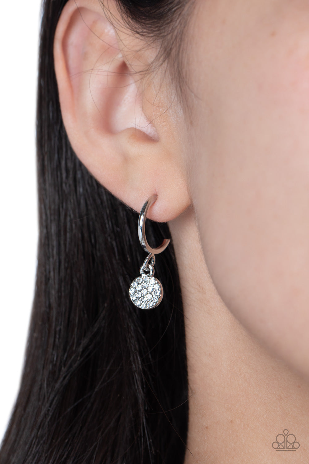 Swinging from a glistening silver hoop, a dainty silver disc, embossed with white rhinestones glimmers, adding a subtle shimmer around the ear. Earring attaches to a standard post fitting. Hoop measures approximately 1/2" in diameter.