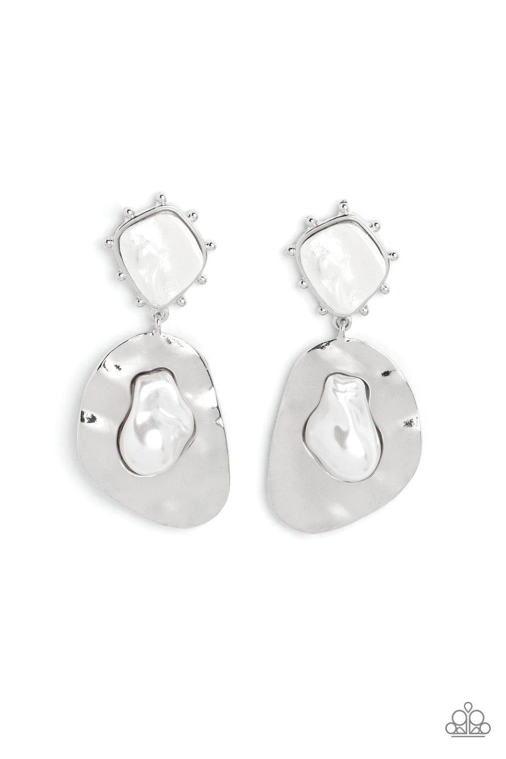 An oversized hammered, asymmetrical silver disc dangles from a more dainty, asymmetrical silver frame, accented with raised silver studs around its edges.