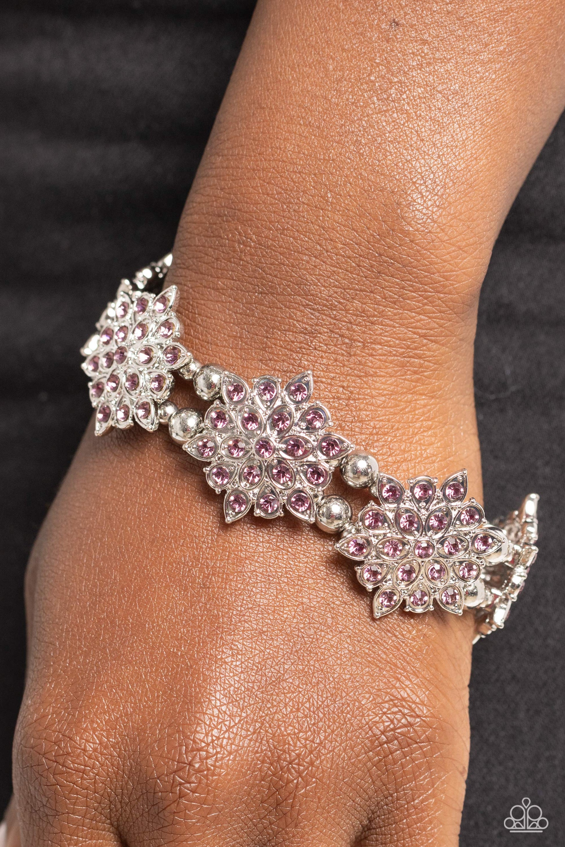 Delicate layers of silver teardrop frames dotted with glistening purple rhinestones combine to create a stunning snowflake-like shape. Infused along elastic stretchy bands around the wrist, the icy frames combine with silver beads in varying sizes for a monochromatic statement.