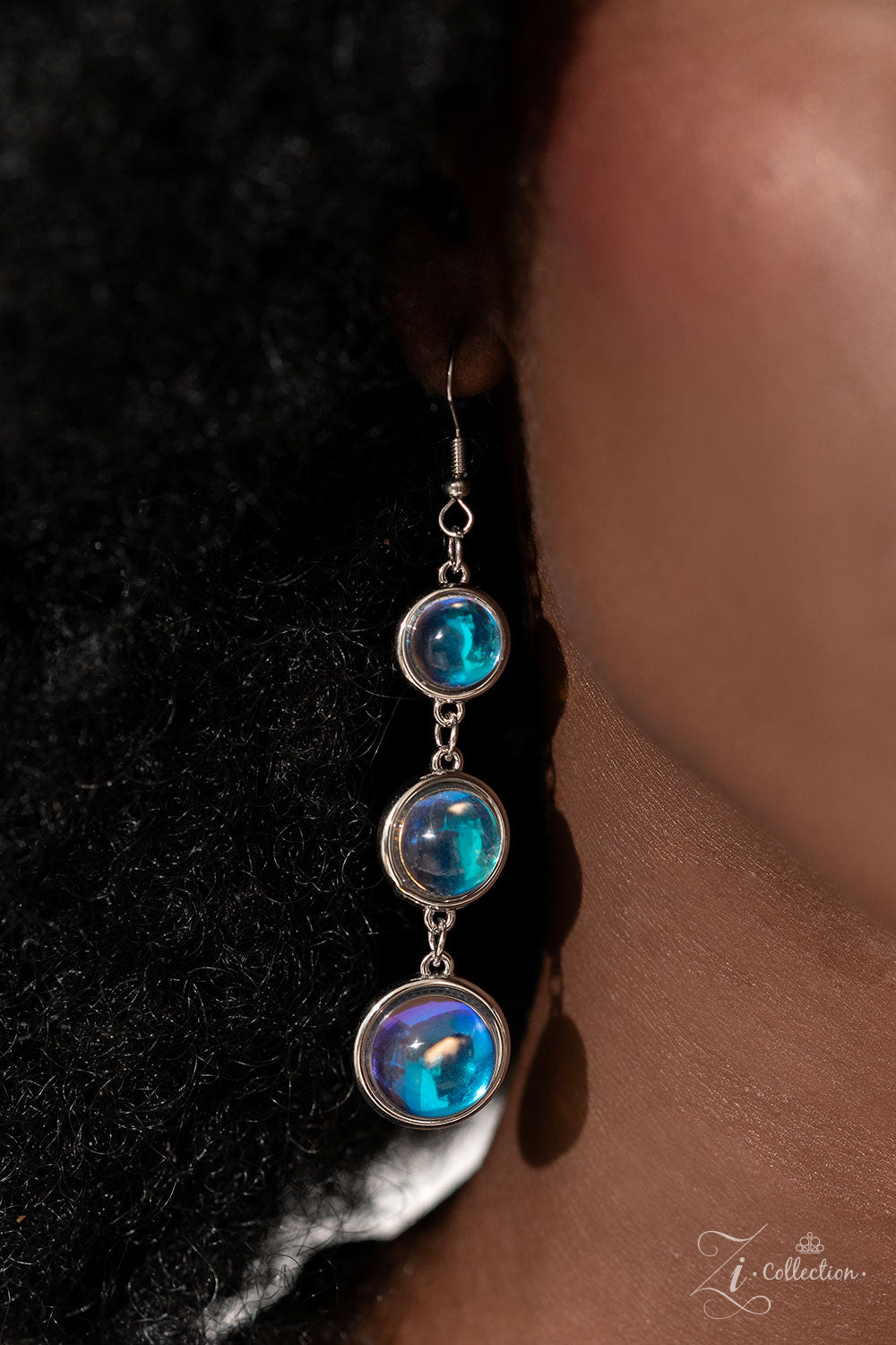 A dizzying display of silver hoops drapes across the chest in effervescent layers. Smooth, glassy beads, brushed in swirls of pastel iridescence, bubble up from some of the open, circular frames, further exaggerating their staggered size and placement, and showcasing their dreamy opalescent finish. With every new angle, a different hue emerges from the glassy beads, mimicking the reflective surface of water in a tropical paradise and emitting an air of serenity. Features an adjustable clasp closure.