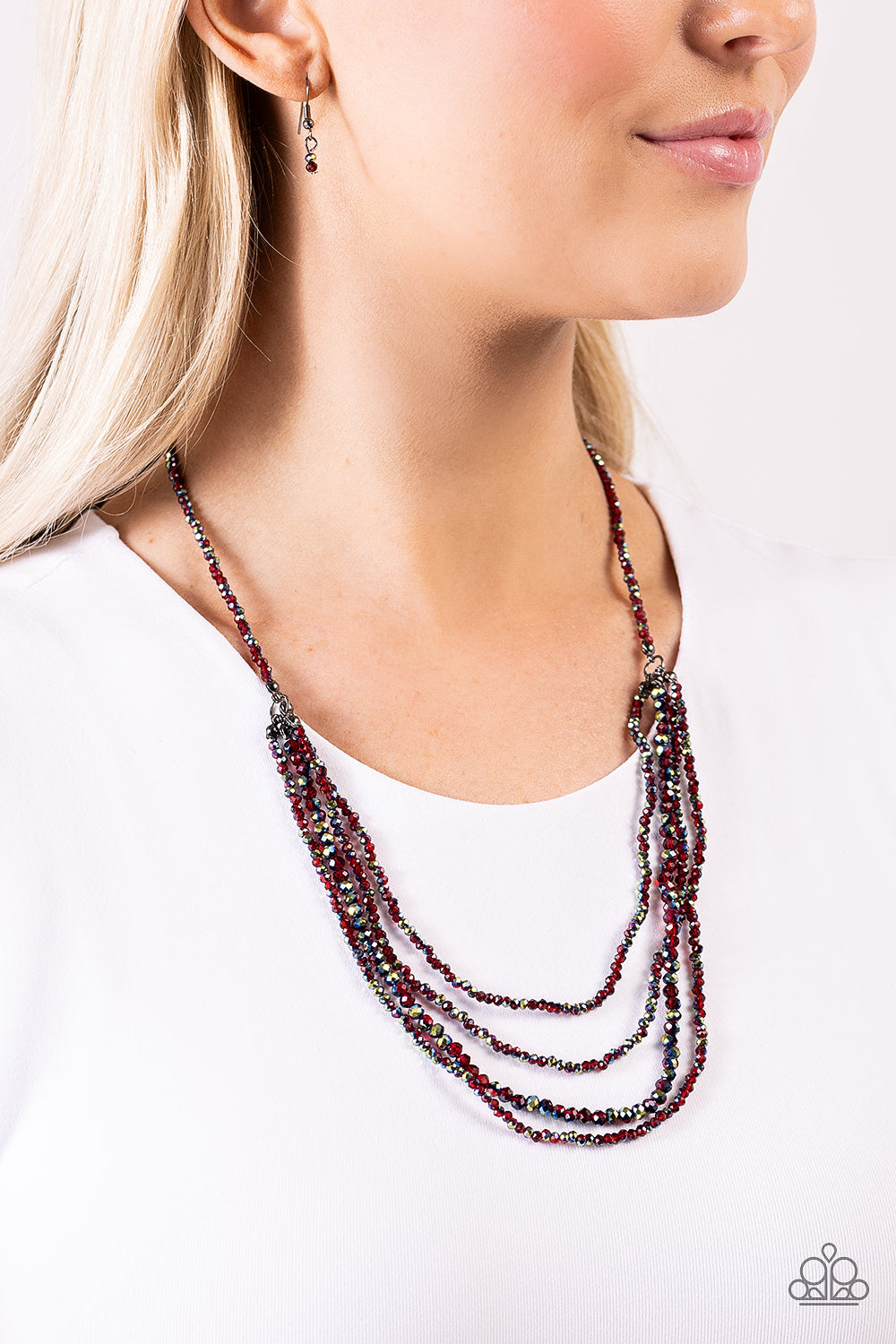 Dipped in a metallic sheen, a strand of faceted red and UV beads coalesce down the chest. Four of the same beaded strands cascade in layers from the single strand for a glamorous finish. Features an adjustable clasp closure.
