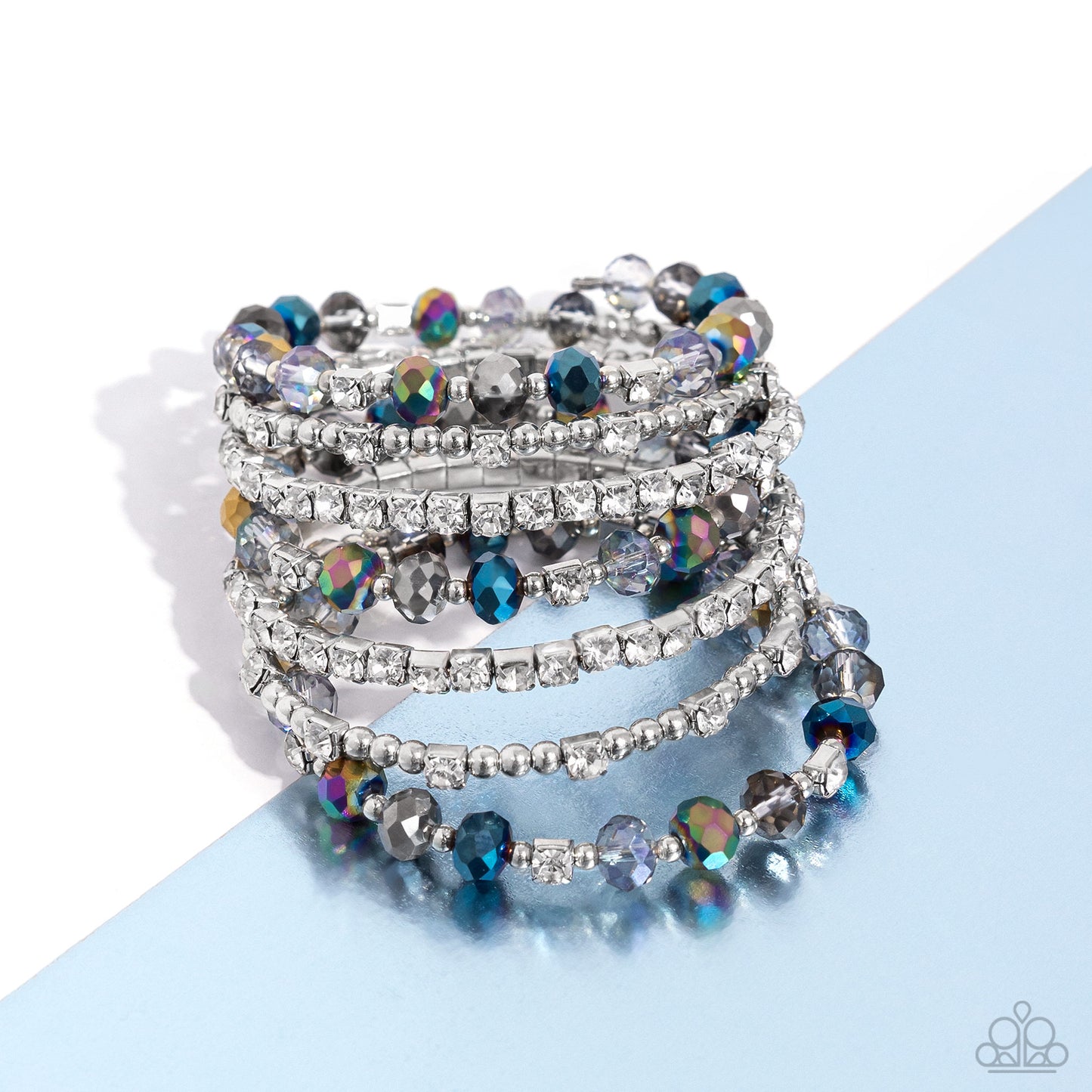 Threaded along a coiled wire, silver beads, white rhinestones in silver square fittings, and oil spill, blue, silver, and transparent faceted beads curl around the wrist, creating an eye-catching, infinity wrap-style bracelet around the wrist.
